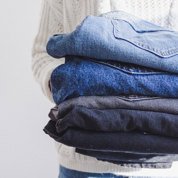woman holding a stack of jeans